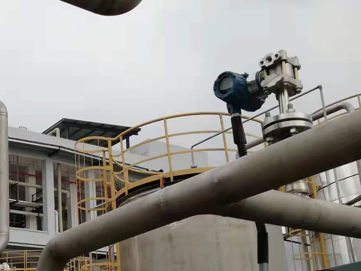 Loop-powered pressure transmitter with armored signal cable installed at a process tank connection