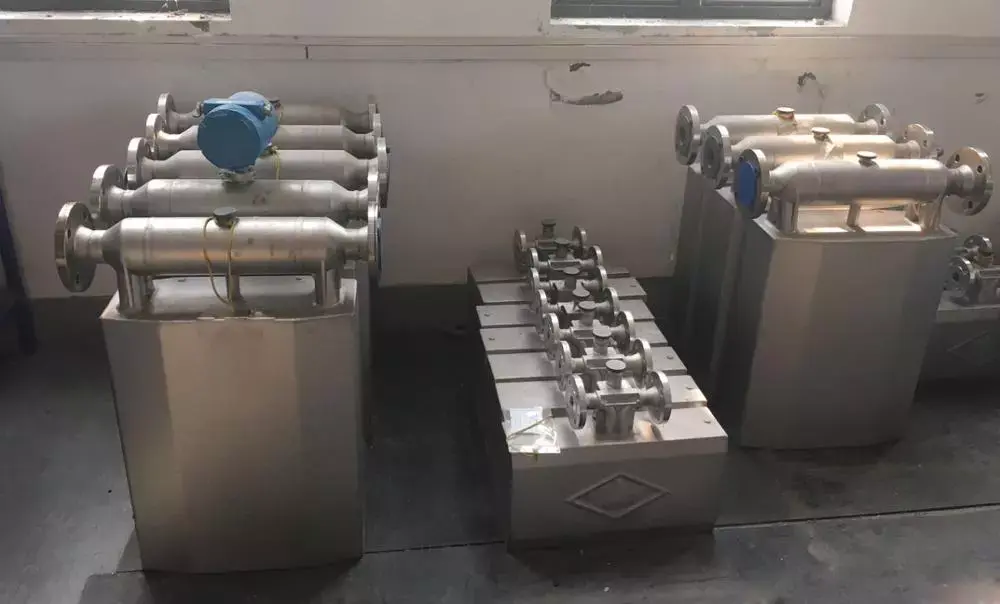 Coriolis mass flow meters with stainless steel measuring tubes staged on a workshop floor
