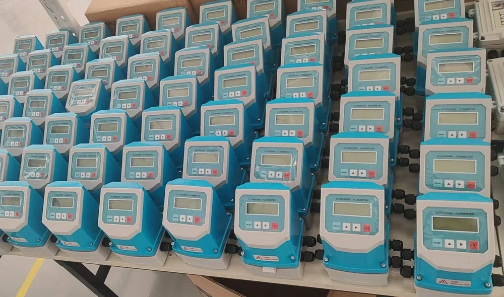 Rows of ultrasonic flow meter converters lined up on a factory bench before final test and shipment