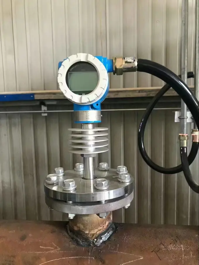 Flange-mounted flow meter with a finned cooling neck welded into a hot process line inside a plant
