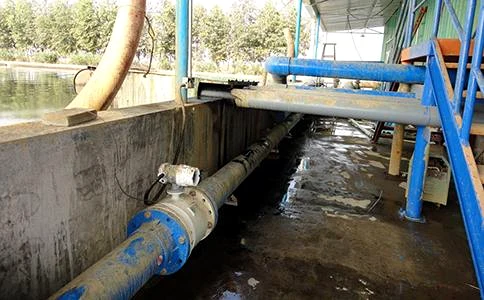 Flow meter on a pump station discharge line beside an open water source