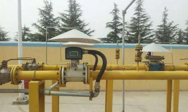 Outdoor gas metering runs with two turbine gas meters under sun shields on yellow piping