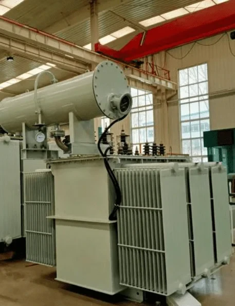Oil-immersed transformer with conservator tank and radiator banks in a factory bay