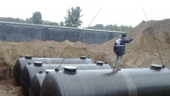 Horizontal steel storage tanks being set in an excavation before burial