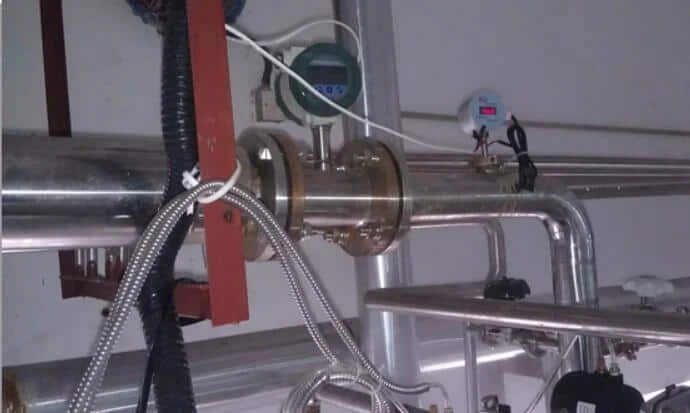 Flanged flow meter in a pipe rack with a temperature transmitter mounted downstream of it and straight pipe on both sides