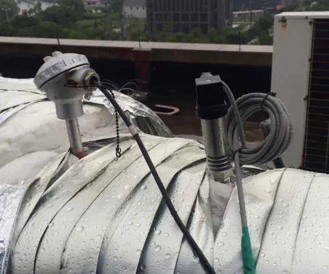 Pressure transmitter and thermocouple threaded into an insulated steam line on a rooftop installation